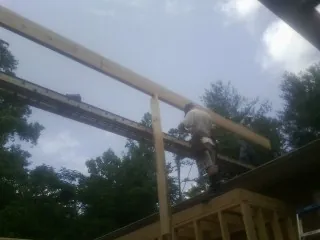 Carpenter setting a ridge beam over a new addition frame in Lisbon