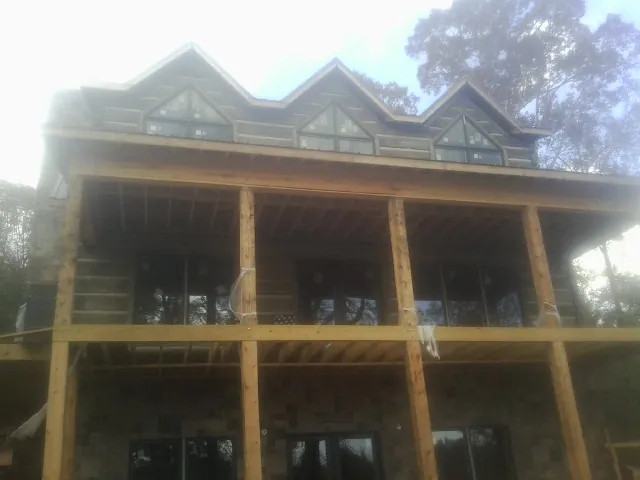 Dormers and porch framing on a large log home under construction — Roof Coating work by our crew in Lisbon